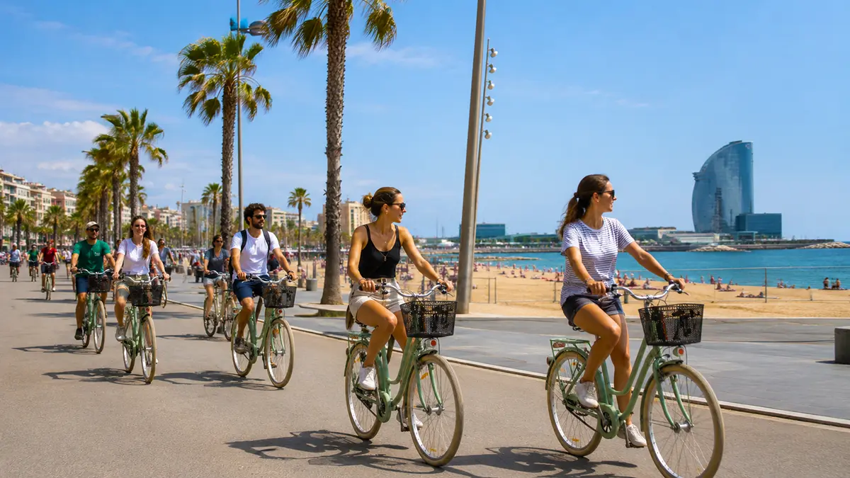 A group of cyclists riding along Barcelona’s sunny beachfront promenade during the Barcelona Bike Tour. Palm trees line the path with the sea and the iconic W Barcelona hotel visible in the distance.