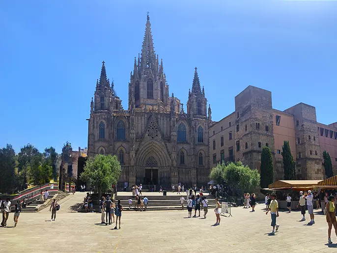 Sunny plaza filled with tourists in front of the iconic Barcelona Cathedral.