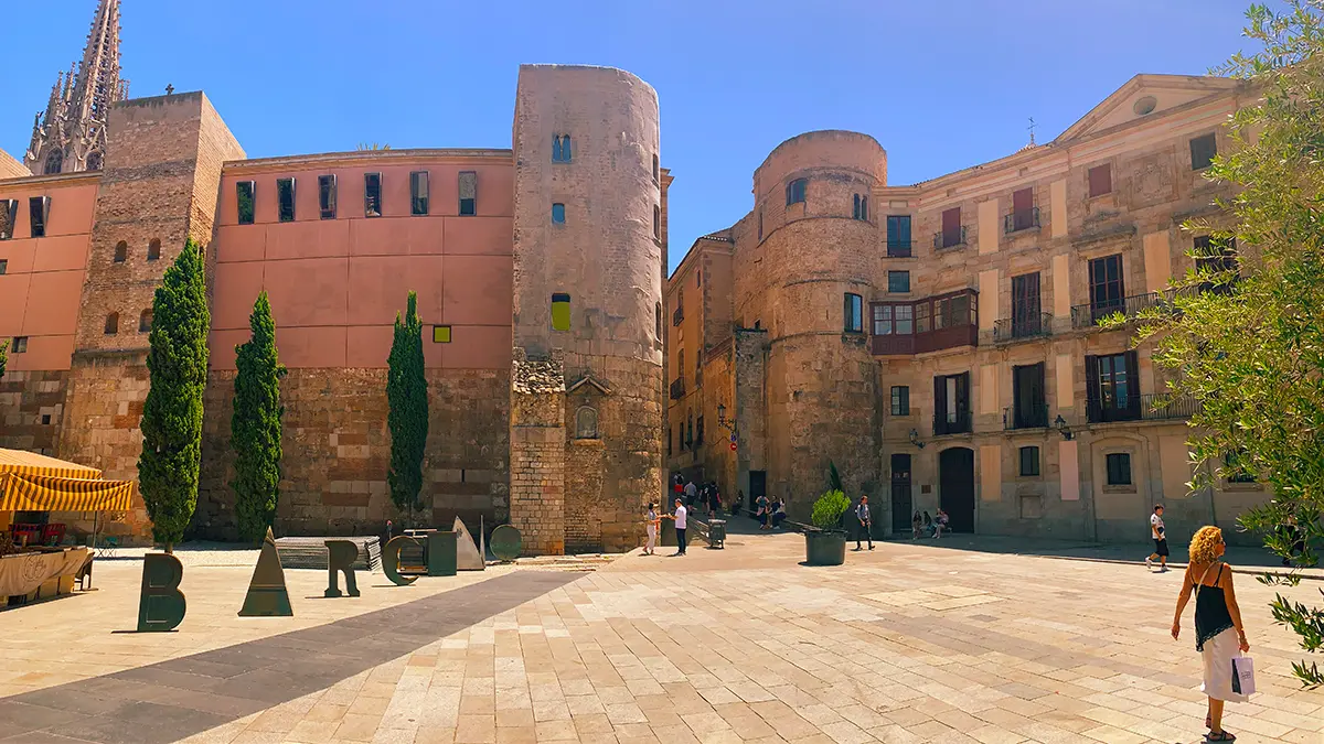 Large "BARCELONA" letters in a historic square surrounded by Gothic architecture.