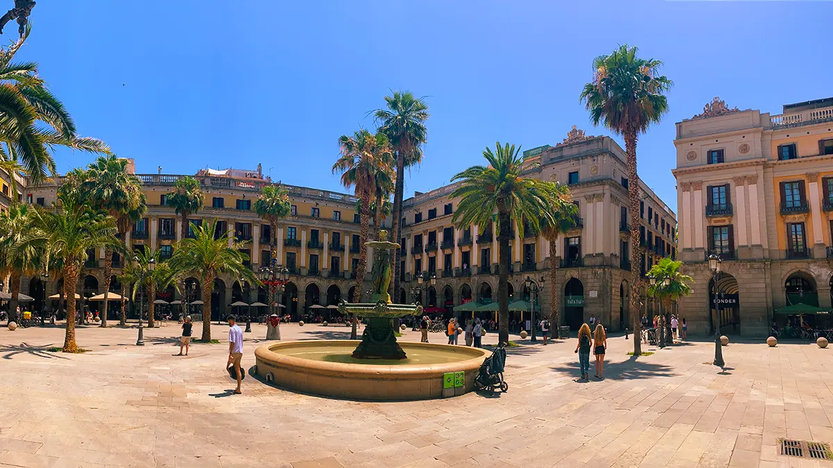 Sunny Plaça Reial with central fountain and palm trees.