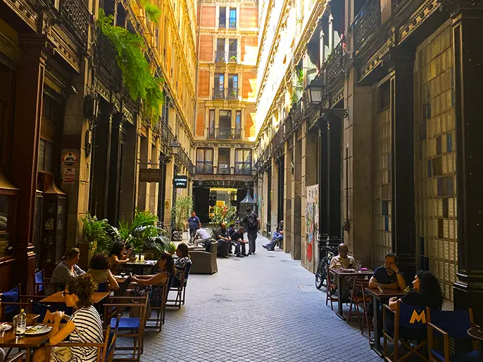 Charming narrow cobblestone street with outdoor cafes in the heart of the Gothic Quarter on the Barcelona Gothic Quarter & Coast Bike Tour.