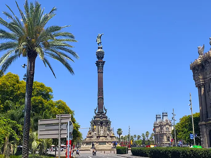 Columbus Monument towering above palm trees at Port Vell.