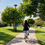 Woman cycling along a tree-lined path in Turia Gardens Valencia on a sunny day.