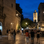 Valencia Museum Night 2026 - Bustling historic street in Valencia at night, crowded with pedestrians near the Centre del Carme (CCCCC) building, with a bell tower visible in the background under twilight skies.