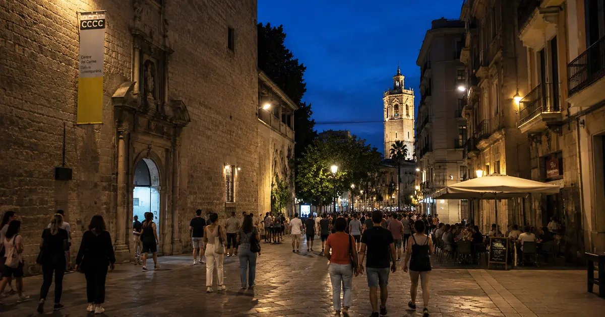 Valencia Museum Night 2026 - Bustling historic street in Valencia at night, crowded with pedestrians near the Centre del Carme (CCCCC) building, with a bell tower visible in the background under twilight skies.